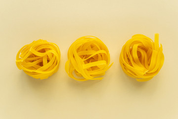 Unprepared wheat pasta in the form of a nest on a beige background. The modern concept of food. Minimalistic layout for designers or website. Mockup, advertising marketing communications