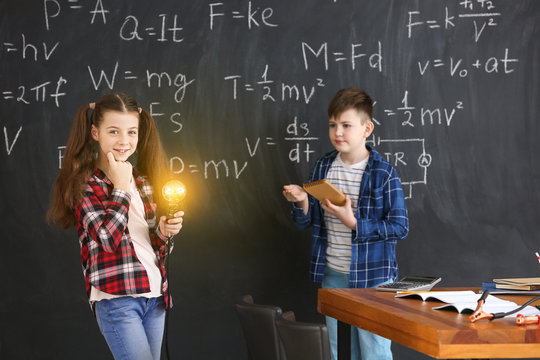 Cute little children near blackboard at physics lesson in classroom