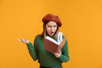 Surprised young woman with book on color background
