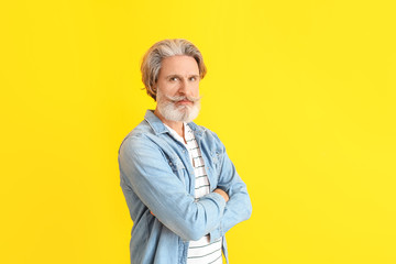 Stylish elderly man on color background
