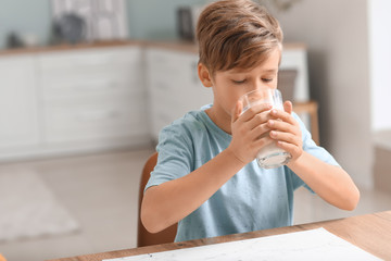 Little boy drinking milk in kitchen