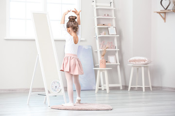 Fototapeta na wymiar Cute little ballerina looking in mirror at home