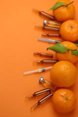 ampoules and Serum with Vitamin C.Tangerines citrus fruits, syringes and ampoules on a bright orange background.   Organic cosmetics concept. Medicine and health concept. pharmaceutical ampoules set .