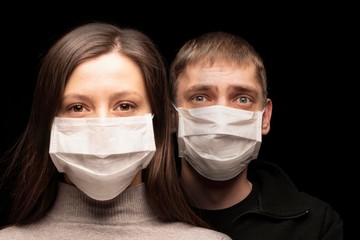 a woman and a man in masks, people are protected from a coronavirus infection. the woman is calm , the man is worried. Studio portrait