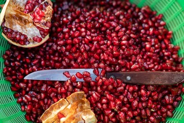 split ripe juicy pomegranate fruit close -up. knife and seeds as background