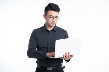 A young Asian man is using his mobile phone and laptop
