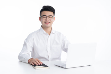 A young Asian man is using his mobile phone and laptop