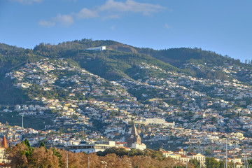 Scenic view of Funchal - capital of Portugal's Autonomous Region of Madeira. Beautiful summer sunny look of small town on hills on paradise tropical island in Atlantic ocean.
