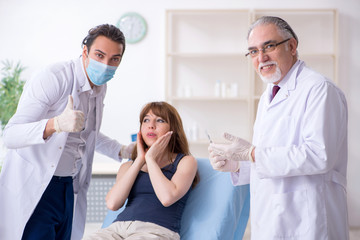 Obraz premium Two male doctors and young woman in plastic surgery concept