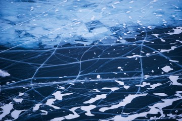 Surface of transparent fissured black ice of The Baikal Lake in winter.