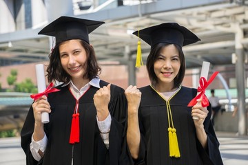 Portrait of happy two women in graduation gowns. Woman in graduation cap. International School. University.