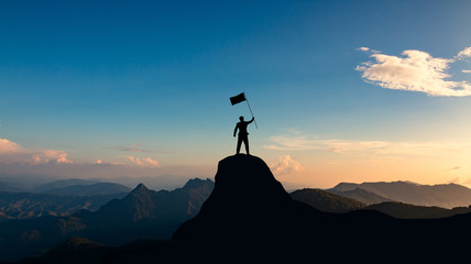 silhouette of businessman with flag on mountain top over sunset sky background, business, success, leadership and achievement concept.