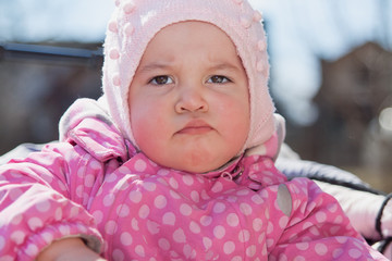 Funny little kid. The little girl is angry. The baby is looking at the camera, a serious face.