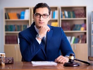 Handsome judge with gavel sitting in courtroom