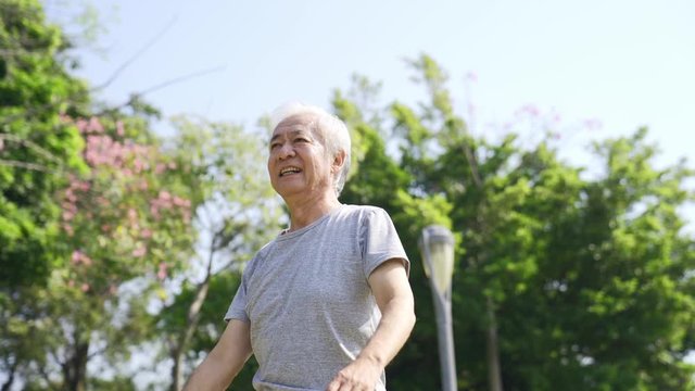 asian senior man walking outdoors stretching arms happy and smiling