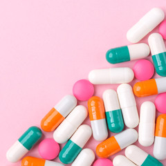 Various pills forming a triangle on a pink background. Concept of pharmacy