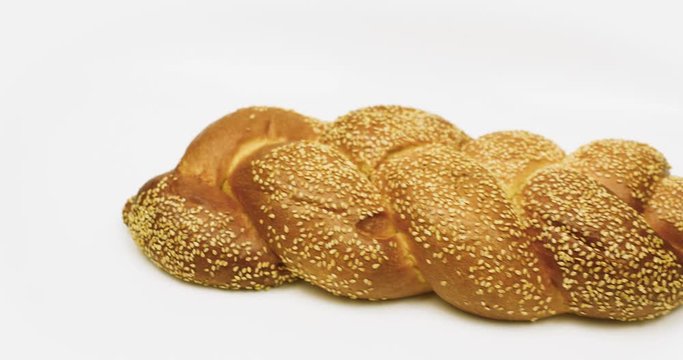 Camera moves from white background to the brown Shabbat challah with seeds