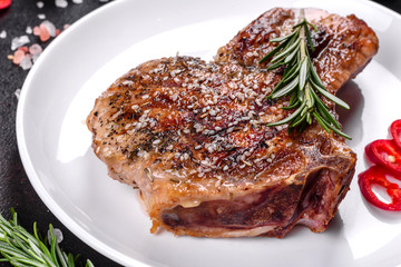 Fresh delicious juicy steak on the bones with vegetables and spices against a dark background