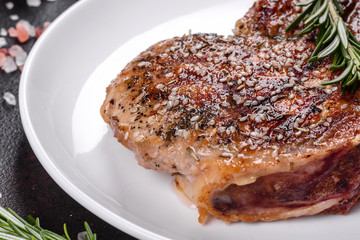 Fresh delicious juicy steak on the bones with vegetables and spices against a dark background