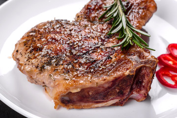Fresh delicious juicy steak on the bones with vegetables and spices against a dark background