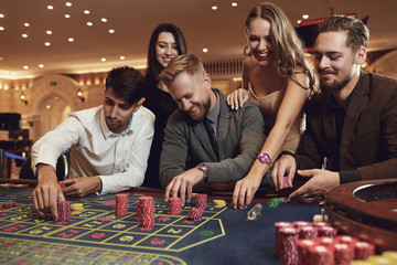 Happy friends play roulette in a casino.