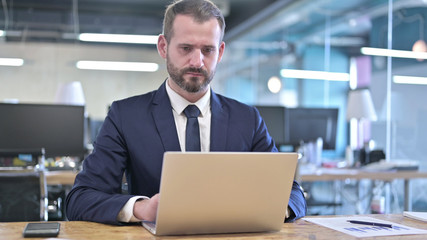 Fototapeta premium The Young Businessman working on Laptop on Office Desk