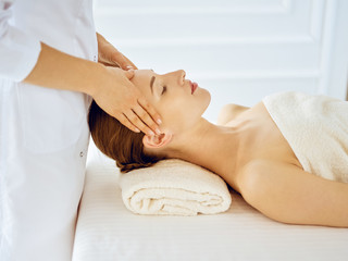 Fototapeta na wymiar Beautiful woman enjoying facial massage with closed eyes. Spa treatment concept in medicine