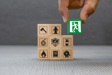 Close-up hand choose a wooden toy blocks with fire exit icon for fire safety protection concepts.