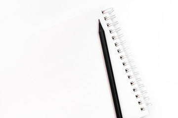 Black pencil on white notebook on white background