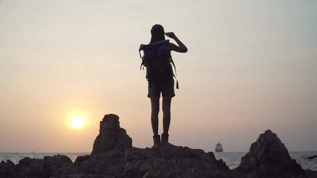 Footage B roll of Hikers Asian women travel to explore the rock by the sea. Outdoors Hiking Silhouette. Climbing, Sea, Hiking Concept. Freedom and belief a success. 