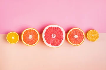 Foto op Plexiglas Slices of different citrus fruits on pink background © Diana Vyshniakova