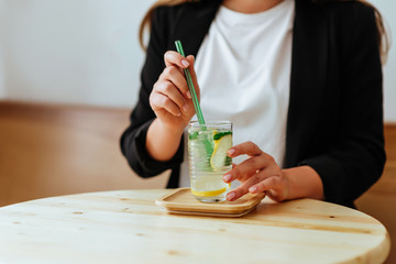 Hand of young woman taking jar of lemonade from table