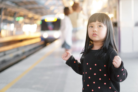 Asian child cute or kid girl waiting sky train or electric train with underground railways or metro subway and happy smiling on railway station or platform in street city for transport holiday travel