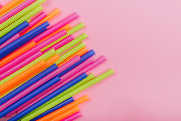 Fototapeta premium colored tubules for juice and cocktails on pink background. Colorful drink straws. straw, plastic free, reusable plastic drinking background, plastic free. Plastic pollution concept.