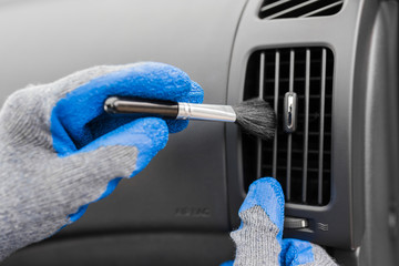 Worker cleaning automobile air conditioner vent grille with brush, closeup. Car wash service