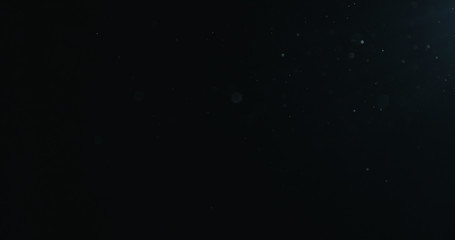 natural dust particles float in air on black background