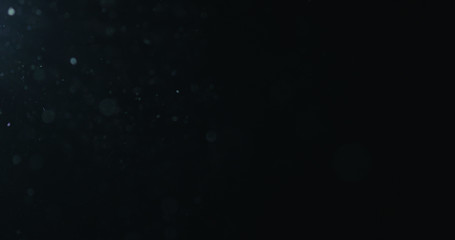 natural dust particles flow in air on black background