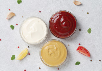 Assortment of sauces: ketchup, mayonnaise and mustard. Different delicious sauces on grey table. Selective focus