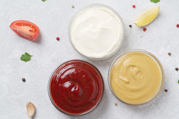 Assortment of sauces: ketchup, mayonnaise and mustard. Different delicious sauces on grey table. Selective focus