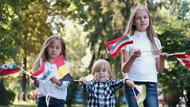 Kids spend time outside in summer. Children are holding flags. Kids learn the flags of different countries.