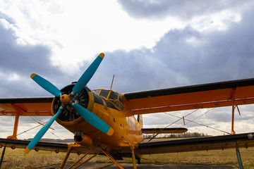 Yellow biplane from front standing on airports with cloud sky