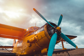 Detail of yellow biplane cabine, engine standing on airports at sunset