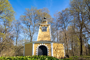 Fototapeta premium View of the old wooden clock tower and park in spring, Kauttua Ironworks area, Finland