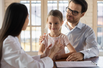 Front view young handsome father in eyeglasses holding on lap smiling cute little daughter,...