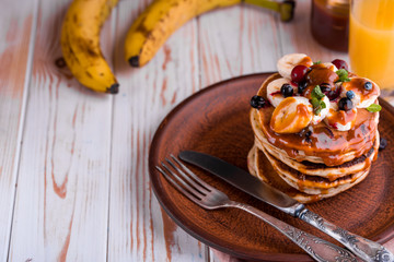 Delicious and lush pancakes with fresh fruits and berries, poured with salted caramel.
