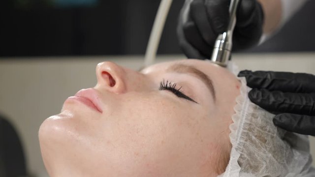 Young attractive woman getting cosmetology procedure in beauty salon. Hardware cosmetology. Anti-aging and anti-wrinkle apparatus cosmetology. Modern relaxing treatment. 4 k footage