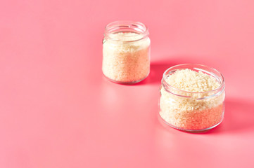 Two jars of grain of rice on pink background. Copy space