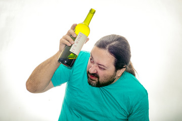 An unshaven young man holds a bottle of wine with both hands and does not stare intently.