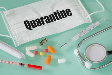hands in medical gloves holding a protective mask with the inscription "Quarantine" medical instruments, thermometer, medicines, test tube with coronavirus