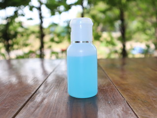 Alcohol spray in clear bottles, used for washing hands. Resting on a wooden table